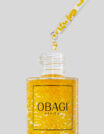 A dropper releasing golden serum from an Obagi bottle.
