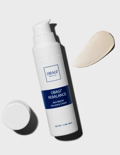 A white bottle of cream with its cap beside it and a dollop of cream on a white surface.