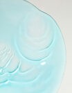 Close-up of a light blue ceramic plate with embossed swirls.