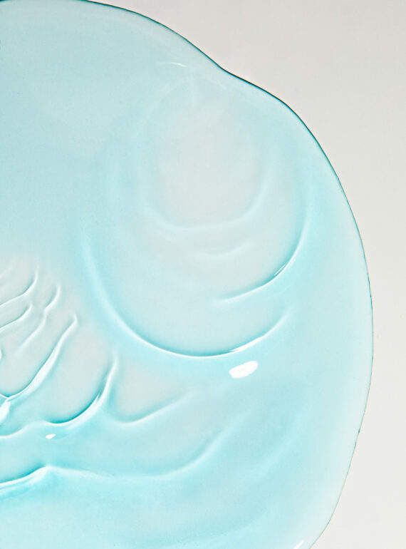 Close-up of a light blue ceramic plate with embossed swirls.