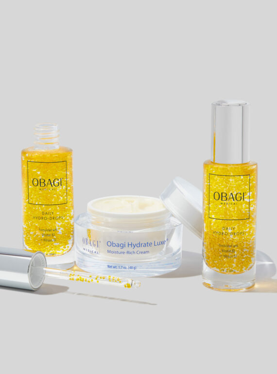 Three skincare products with yellow liquid and cream on a white surface.
