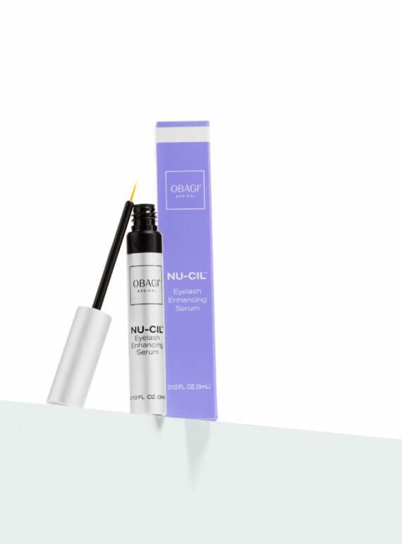 A mascara tube with its wand beside a purple box on a white surface.