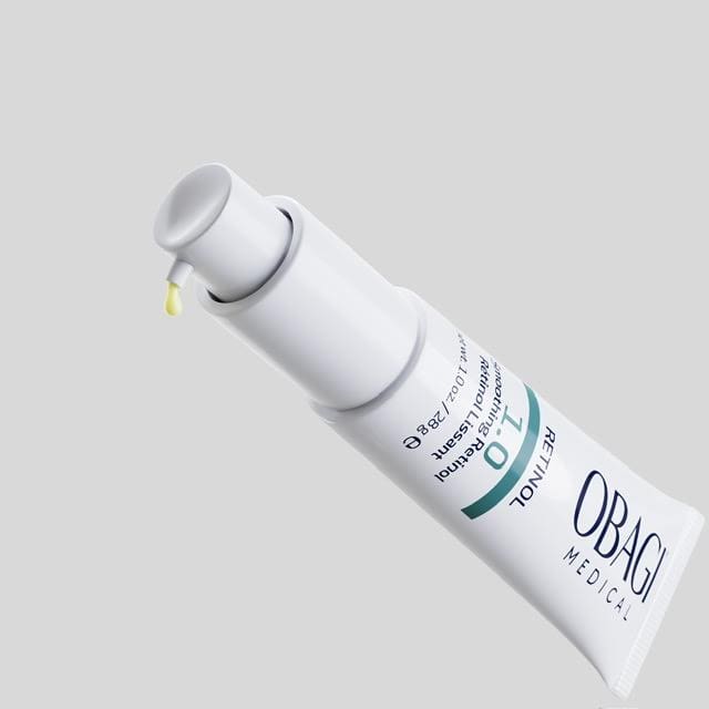 A white tube of OBAGI skincare product with a drop of cream.