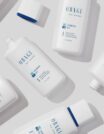 A flat lay of white skincare product bottles with blue accents on a light background.