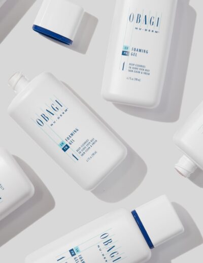 A flat lay of white skincare product bottles with blue accents on a light background.