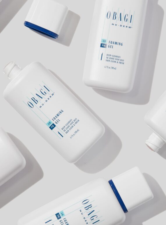 A flat lay of white skincare product bottles with blue accents on a light background.